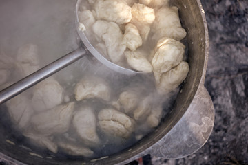 The process of boiling of dumplings in a cauldron, close up.
