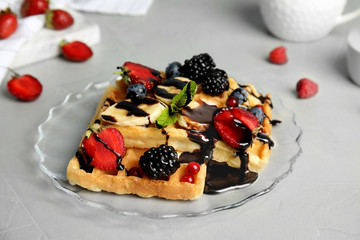 Delicious waffles with fresh berries served on grey table