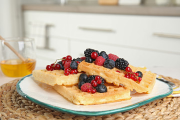 Delicious waffles with fresh berries served on table in kitchen