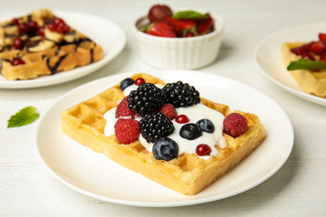 Delicious waffle with fresh berries served on white wooden table