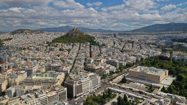 Aerial photo of famous Greek Parliament building in Syntagma square and Lycabettus hill at the background with beautiful clouds and deep blue sky, Athens, Attica, Greece