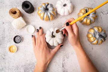 Female hands with black nails painting pumpkins for halloween