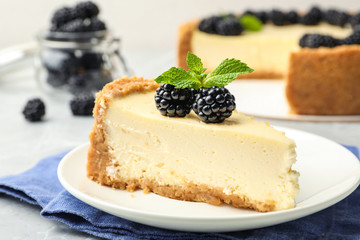 Piece of delicious cheesecake with blackberries on table, closeup