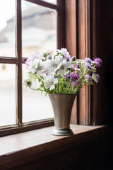 Fototapeta na wymiar Summer flowers in an old window