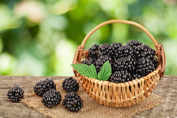blackberry in basket on the wooden table with leaf isolated on a white background closeup