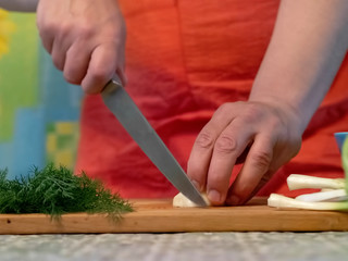 Obraz premium Cook cuts onions on a chopping Board Man cuts vegetables in the kitchen
