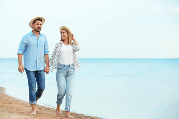 Happy romantic couple walking on beach, space for text