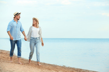 Happy romantic couple walking on beach, space for text