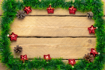 Fototapeta na wymiar Christmas background. Frame made of tinsel with decorations and cones. Wood background.