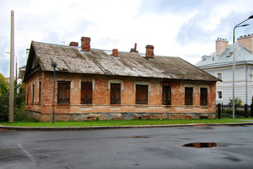 Fototapeta premium old brick house on the street with shuttered windows and roof pipes