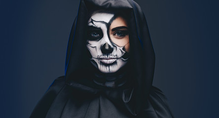 Fototapeta na wymiar Young female in hooded cape with scary makeup