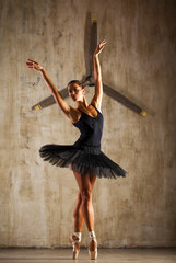 Fototapeta na wymiar Young beautiful ballerina in black ballet tutu posing in dark studio