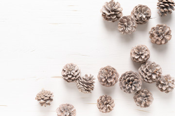 Christmas, New Year or Noel holiday festive winter greeting card with pine cones on white wooden background, xmas flat lay composition, top view, space for text