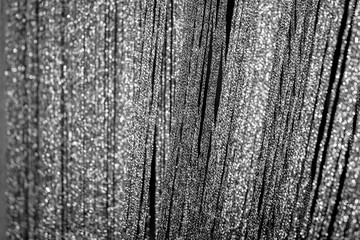 Silver curtains made of shiny threads. Abstract Christmas or New Year blurred background. Black and white.