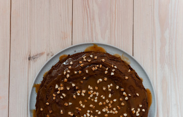 Chocolate cake with nuts. Top view delicious dark chocolate cake on the wood table. A biscuit cake is sprinkled with walnut with chocolate cream. Closeup