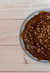 Chocolate cake with nuts. Top view delicious dark chocolate cake on the wood table. A biscuit cake is sprinkled with walnut with chocolate cream. Closeup