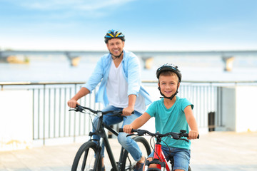 Naklejka premium Dad and son riding bicycles together outdoors