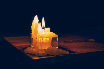 Burning candle stands on a wooden table in the dark