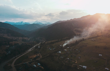 Village in carpathian mountains spring evening and snow peaks hills on background shooting on quadcopter