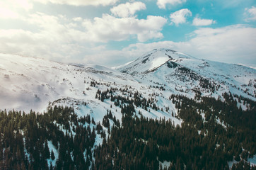 Sunny winter carpathian mountains with snow blue sky clouds shooting on quadcopter