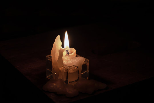 Fire candle stands on a wooden table in the dark