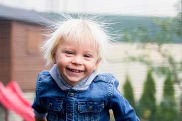 Cute little boy with static electricy hair, having his funny portrait taken outdoors