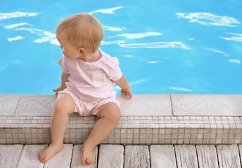 Fototapeta premium Little baby sitting near outdoor swimming pool. Dangerous situation