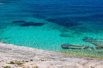 Fototapeta na wymiar Stone beach on Proizd Island near Korcula Island, Dalmatia, Croatia, blue lagoon, clear emerald sea water, popular tourist destination 