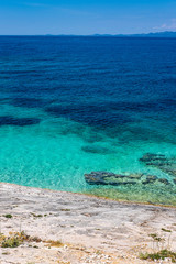 Stone beach on Proizd Island near Korcula Island, Dalmatia, Croatia, blue lagoon, clear sea water and blue sky, popular tourist destination  