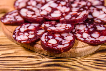 Cutting board with sliced salami sausage on a wooden table