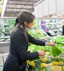 Woman choosing vegetables on counter in  market.