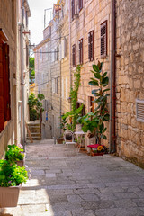 Narrow stone street with stone houses and facades and flowers in historic fortified Korcula town, Korcula Island, Dalmatia, Croatia