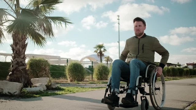 Man with paralysis of legs muscles is sitting in invalid carriage and riding