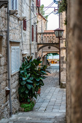 Narrow stone street with stairs, stone facades and houses with balcony and flowers in front in the centre of historic old town of Korcula, Korcula Island, Dalmatia, Croatia