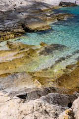 Stone beach on Proizd Island near Korcula Island, Dalmatia, Croatia, blue lagoon, clear sea water and blue sky, popular tourist destination