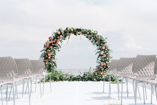 The round wedding arch is decorated with a variety of fresh flowers and greens.