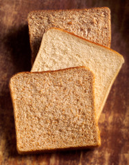 one slice of wholemeal, white and brown bread against wood background