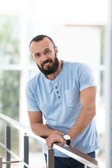 Portrait of handsome mature man leaning on handrail indoors