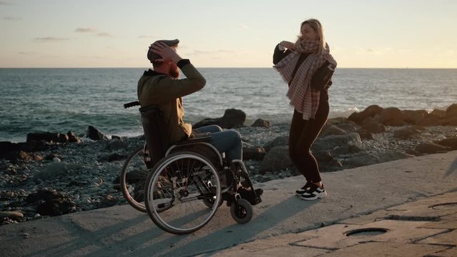 Cheerful disabled man and woman are having fun and dancing on sea embankment