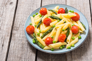 Penne pasta salad with asparagus , tomatoes and peas