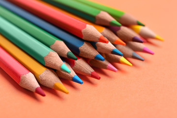 Different color pencils on coral background, closeup
