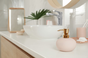 Elegant pink dispenser on light countertop in bathroom interior