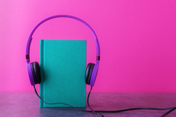Green notebook with violet headphones over pink background