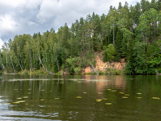 landscape with beautiful sandstone cliffs, green trees, water reflections, Brasla river, Latvia