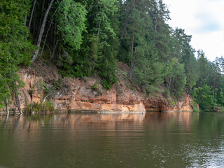 landscape with beautiful sandstone cliffs, green trees, water reflections, Brasla river, Latvia