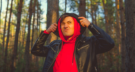 Man standing beside trees in sunny day. Portrait of young man in casual clothes posing among trees