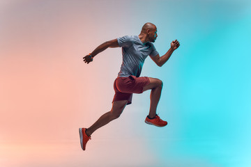 New champion. Full length of young african man in sports clothing jumping against colorful background - obrazy, fototapety, plakaty