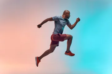 Poster Nieuwe kampioen. Volledige lengte van jonge Afrikaanse man in sportkleding die tegen kleurrijke achtergrond springt © Friends Stock