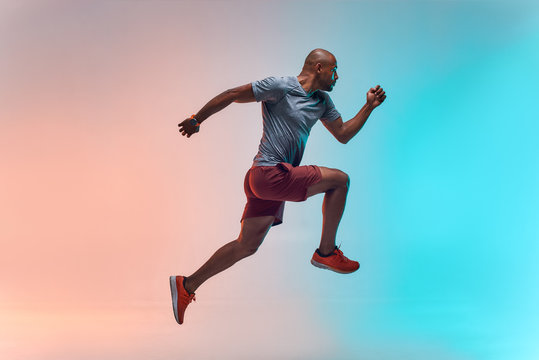 New champion. Full length of young african man in sports clothing jumping against colorful background