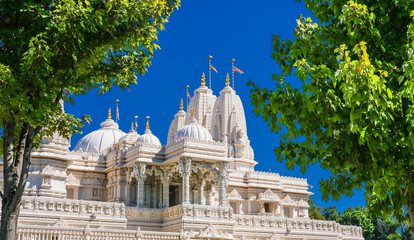 Hindu Mandir against a blue sky between green trees